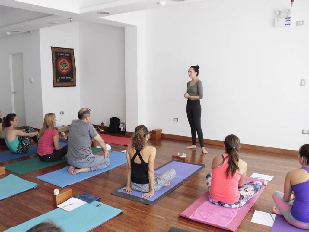 Sandra Rovegno dictando clases de yoga en un estudio de yoga bonito, de paredes blancas.