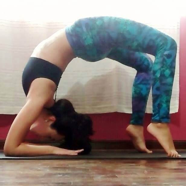 Sandra Rovegno haciendo una postura de yoga donde invierte su cabeza.